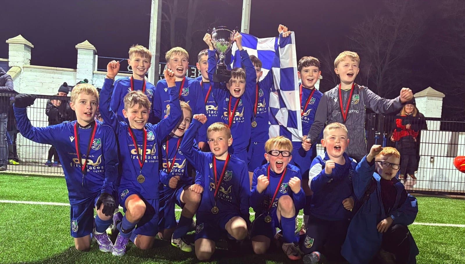 Kilmore Rec young players celebrating a cup win under floodlights